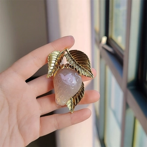 Detailed close-up of a vintage strawberry brooch with gold leaves and resin berry