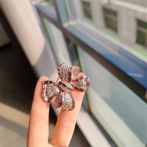 Broche nœud élégante avec zircons et cristaux en or rose tenue dans la main