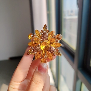 Vista macro de un broche de flor en cristal ámbar con baño de oro y detalles de diamantes