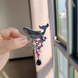 Detail of vintage whale brooch with blue rhinestones, pearls and a large crystal drop