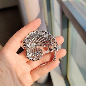 Close-up of vintage silver feather brooch with hollow brushed metal texture details