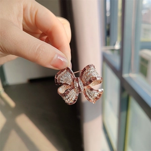 Gros plan d'une broche nœud en or rose avec des zircons étincelants sur une main