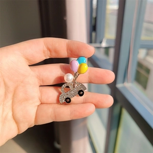 Détail d'une broche camion avec des ballons colorés et une perle élégante