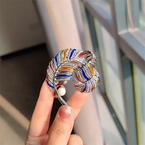 Detail of vintage gold feather brooch with colorful enamel, rhinestones and a white pearl