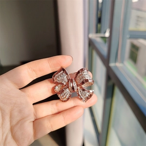 Exquise broche nœud dorée à l'or rose ornée de zircons brillants et de cristaux fins