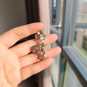 Vue arrière détaillée d'une broche fleur dorée montrant le fermoir et le métal texturé