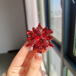 Vista detallada del broche de flor con diamantes rojos y una elegante base de metal dorado