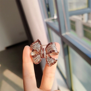Gros plan détaillé d'une broche nœud en zircon avec cristaux roses sertis d'or rose