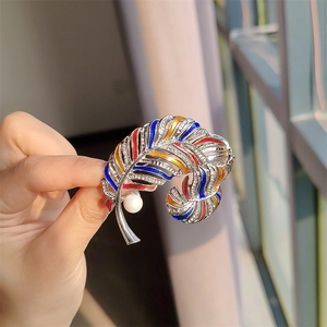 Vintage feather brooch with colorful enamel and pearl accents in golden finish