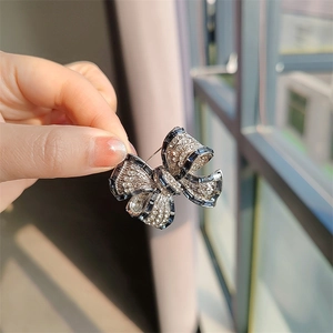 Gros plan sur une broche nœud avec zircon bleu et strass scintillants tenue à la main