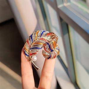 Close-up of a vintage golden feather brooch with colorful enamel and inlaid rhinestones