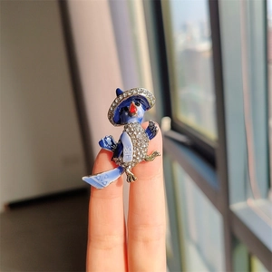 Detailansicht einer blauen Emaille-Papageienbrosche mit funkelnden weißen Strasssteinen