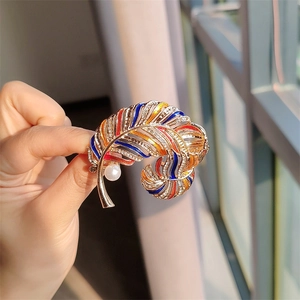 Detail of colorful enamel feather brooch with sparkling rhinestones and a white pearl