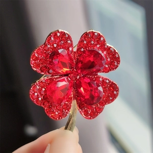 Detailed close-up of red clover brooch with sparkling crystals and golden alloy setting