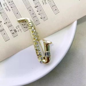 Exquisite gold saxophone brooch with sparkling rhinestones on a vintage music sheet