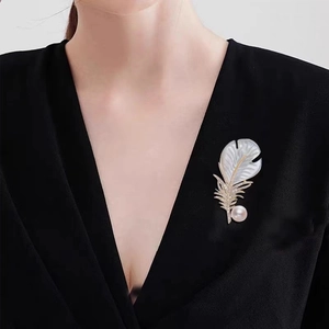 Broche plume en nacre blanche avec perles et cristaux sur un blazer noir chic