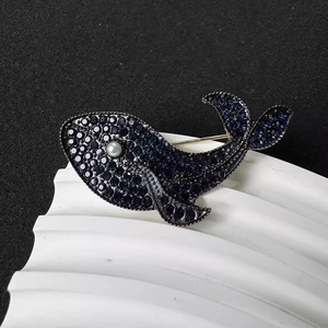 Elegant blue whale brooch with crystals and pearl eye on a wavy textured base