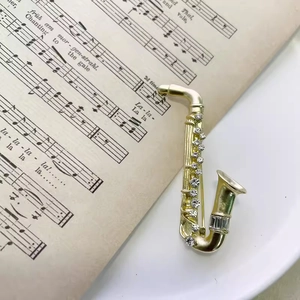 Elegant gold saxophone brooch with sparkling rhinestones on vintage music sheet background