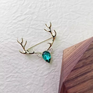 Broche bois de cerf dorée ornée d'un cristal vert foncé en forme de poire
