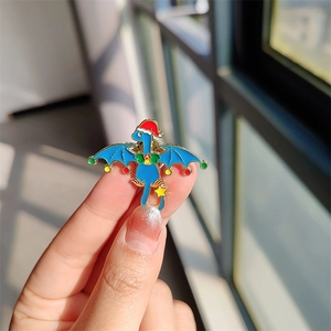 Détail d'un pin's en émail dragon de Noël bleu avec bonnet de fête et une étoile