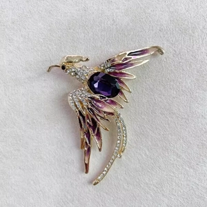 Détail de la broche phénix de luxe avec pierre violette et accents en cristal