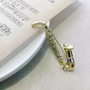 Detailed close-up of saxophone brooch with gold plating and sparkling rhinestones