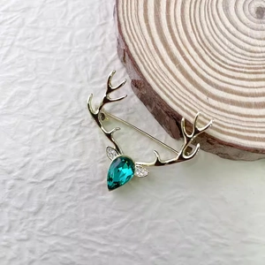 Détail de la broche renne doré avec pierre précieuse vert émeraude et zircons blancs