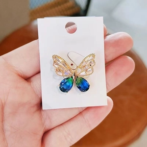 Spilla a farfalla dorata con cristalli blu e strass rosa su un cartoncino