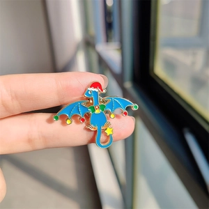 Vue rapprochée d'un pin's en émail dragon bleu de Noël avec chapeau rouge et étoile