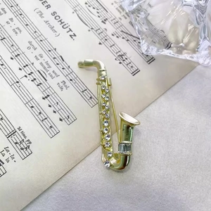Elegant gold saxophone brooch with sparkling rhinestones on vintage sheet music