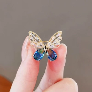 Squisita spilla a farfalla dorata con cristalli blu e pietre di zircone cubico bianco