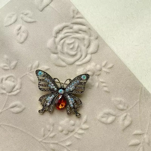 Vintage gold butterfly brooch with a large red teardrop stone and colorful rhinestones
