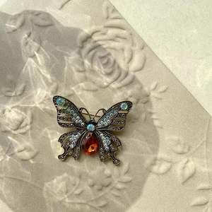 Macro shot of vintage butterfly brooch with orange gemstone and crystal butterfly wings