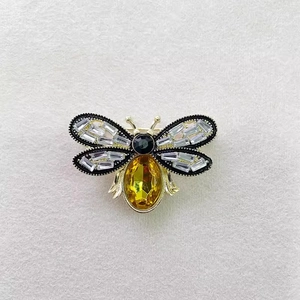 Close-up of golden bee brooch with rectangular zircons and a large yellow gemstone