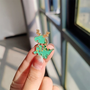 Vue détaillée d'une broche en émail dinosaure de Noël vert avec des bois de renne