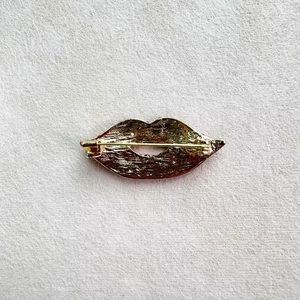 Macro detail of the gold-plated lip brooch back with sturdy safety pin and hammered texture