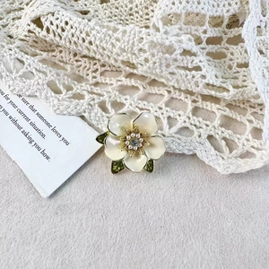 Détail d'une élégante broche gardénia avec base dorée et décorations en perles