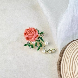 Elegante spilla a rosa rosa corallo con stelo dorato, perle e strass scintillanti