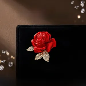 Détail macro de la broche rose rouge avec feuilles dorées serties de cristaux