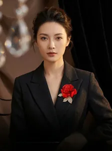 Détail d'une broche rose en tissu rouge avec feuilles dorées en strass sur costume noir