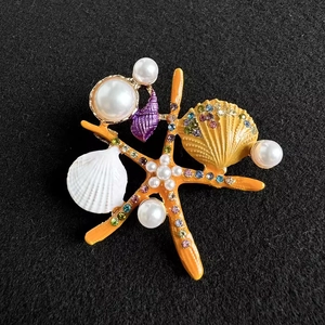 Broche étoile de mer et coquillage avec strass colorés et perles sur fond noir