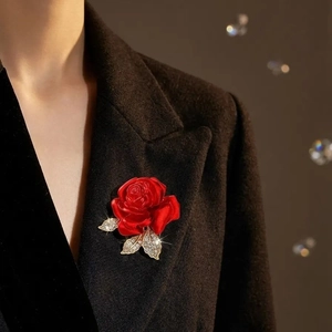 Élégante broche rose rouge avec feuilles en cristal sur une veste de costume sombre