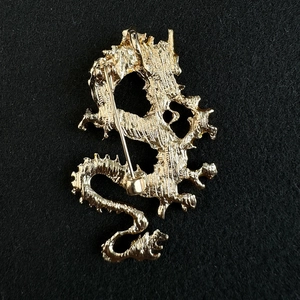 Detailansicht der Rückseite der goldenen Drachenbrosche mit stabiler Sicherheitsnadel