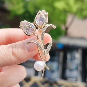 Eleganter Tulpen-Brosche in Gold mit Kristallen und Perle im Handvergleich