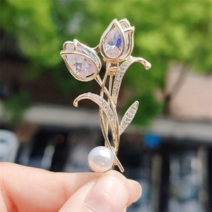 Elegante Gold-Tulpen-Brosche mit Zirkonia-Blüten und weißer Perle auf grünem Grund