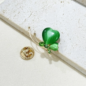 Elegant gold butterfly brooch with green opal wings and crystal accents on stone background