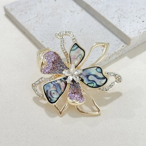 Elegant gold flower brooch with purple rhinestones and iridescent abalone shell petals