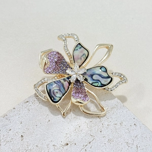 Elegant gold flower brooch with purple rhinestones and iridescent abalone shell petals