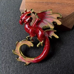 Détail d'une broche dragon rouge et or avec une finition émaillée sophistiquée