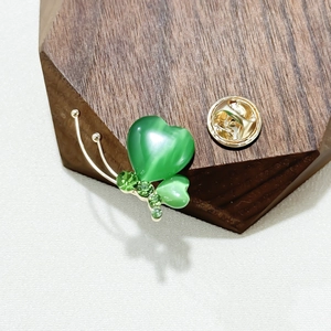 Exquisite butterfly brooch with green cat-eye wings and sparkling crystals on wooden base